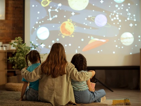 A woman and two young girls watching a projected image