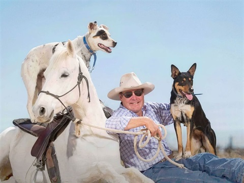 Outback Jack with his white horse and two dogs seated