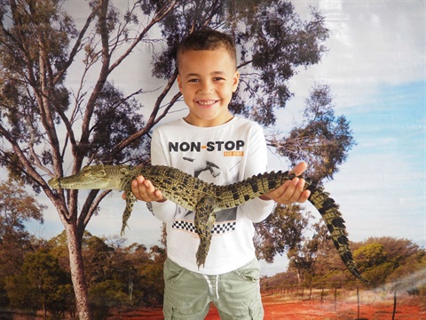 A young boy holding a baby crocodile