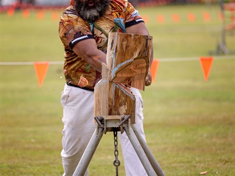 A main chopping a log in a woodchop competition at a show